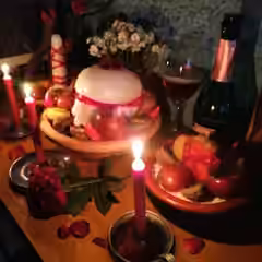 Oferenda com velas, flores e frutas num altar.